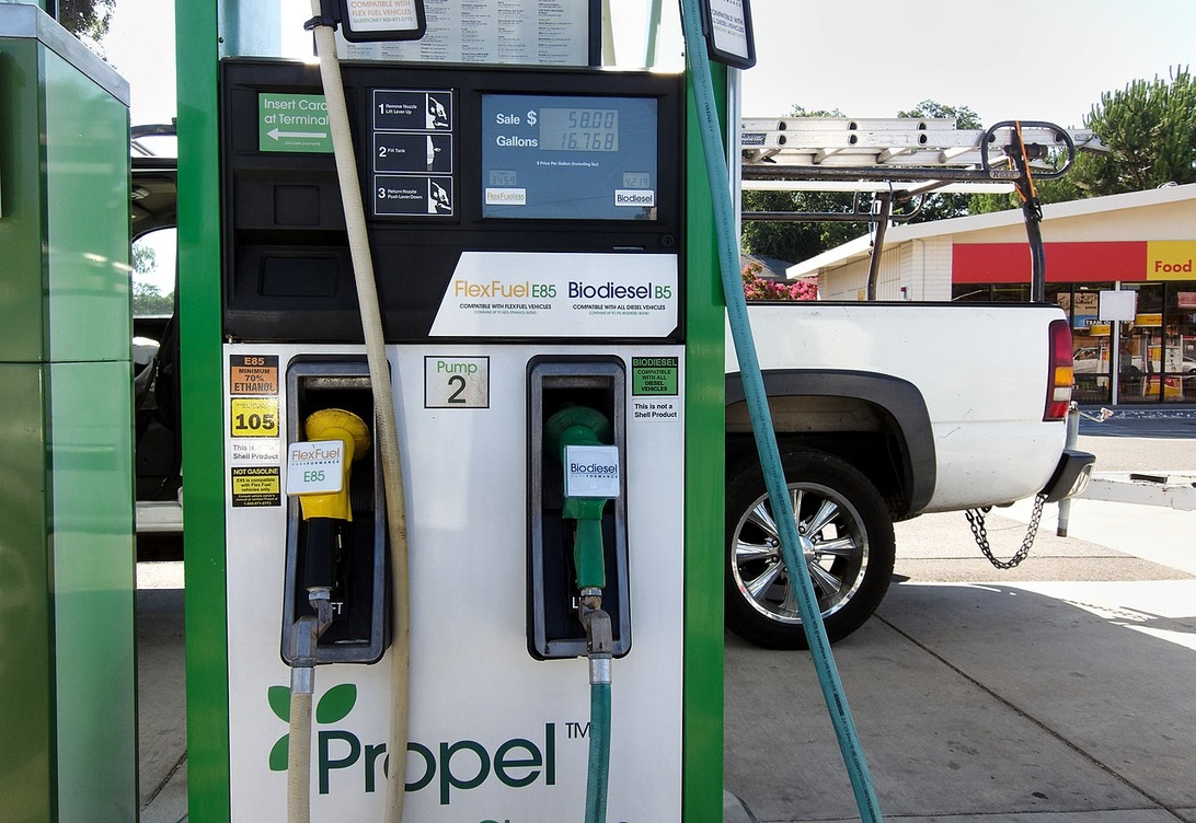 En E85-pump på en bensinstation bredvid en laddstation för elbilar.